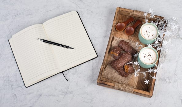 Coffee cups and chocolate coated gingerbread in a wooden basket, empty copy space, christmas season