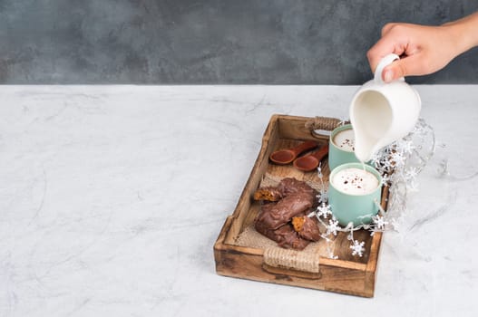 Coffee cups and chocolate coated gingerbread in a wooden basket, empty copy space, christmas season