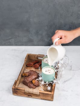 Coffee cups and chocolate coated gingerbread in a wooden basket, empty copy space, christmas season