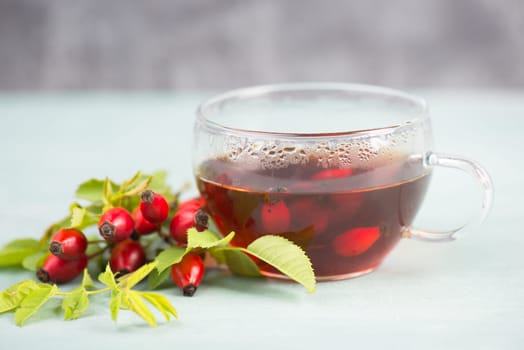 Hip rose tea with fresh fruits and leaves, hot drink