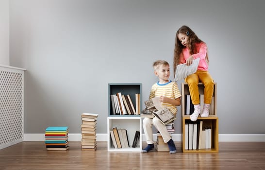 Two children sitting in the room and reading books. Concept of education and friendship.