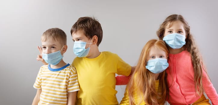 Group of four children in medical mask standing indoor. Concept of education during the pandemic of Covid-19 and human relationship.