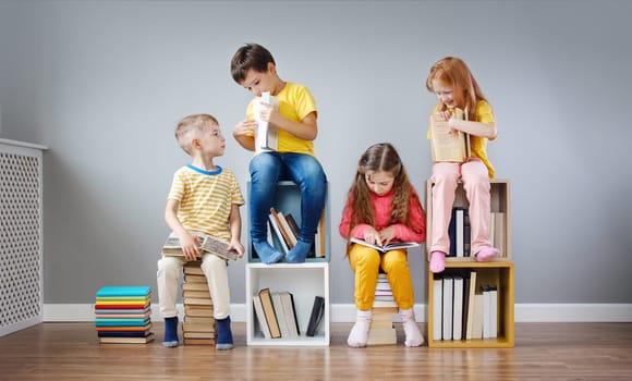 Group of children sitting on the book's stacks and on the bookshelves in the room and reading periodical. Concept of education and friendship.