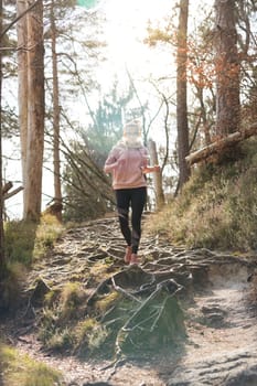 Active sporty woman listening to the music while running in autumn fall forest. Female runner training outdoor. Healthy lifestyle image of young caucasian woman jogging outside.