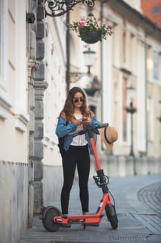 Electro-mobility. Traveler unlocking an e-scooter using an app on her smartphone. Traveler exploring old town on environmentally friendly electric scooter.