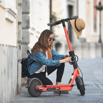 Electro-mobility. Traveler unlocking an e-scooter on the street. Traveler exploring old town on environmentally friendly electric scooter.