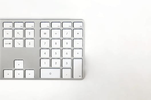Detail of a modern white computer keyboard on a white table. Computer hardware device. Technology and internet