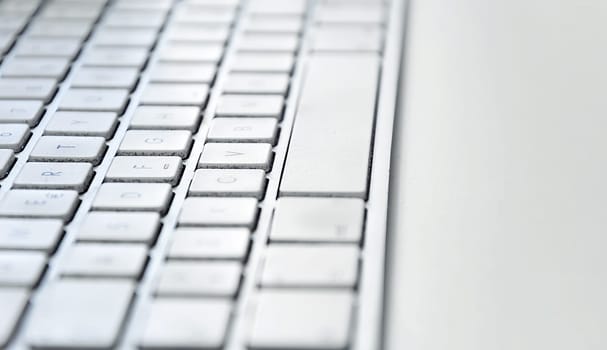 Detail of a modern white computer keyboard dirty and dusty on a white table. Computer hardware device. Technology and internet