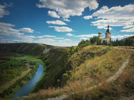 Scenic view from the hills to the Raut river at Orheiul Vechi (The old city of Orhei). Christian monastery on top of the cliff at Butuceni village, Moldova.