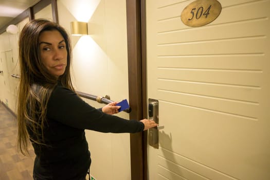 Latin Woman opens a door with a keycard in a hallway, key electronic lock, hotel room, holidays in mallorca, spain.