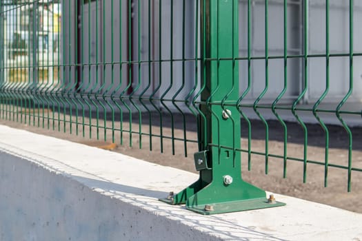 Steel lattice green fence with wire. Fencing. Grid industrial wire fence panels, pvc metal. Installation of sectional fencing. Welded mesh fence. Installation of a grid for fencing the territory