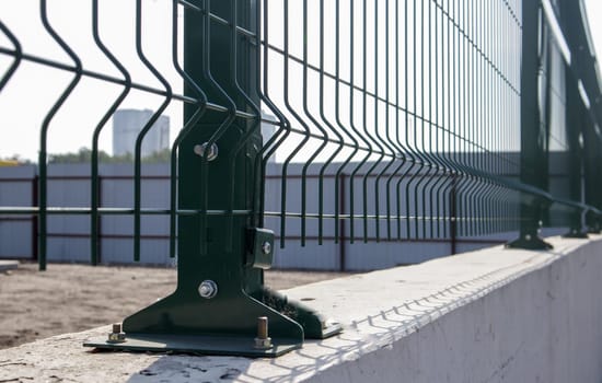 Steel lattice green fence with wire. Fencing. Grid industrial wire fence panels, pvc metal. Installation of sectional fencing. Welded mesh fence. Installation of a grid for fencing the territory