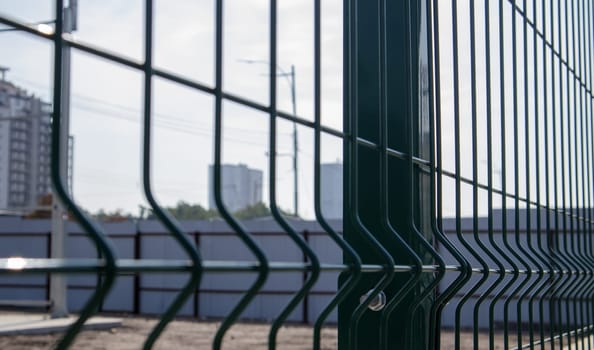Steel lattice green fence with wire. Fencing. Grid industrial wire fence panels, pvc metal. Installation of sectional fencing. Welded mesh fence. Installation of a grid for fencing the territory