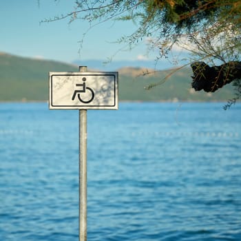 Sign for a handicapped accessible beach on the otherwise rocky coast of the Adriatic Sea near Krk in Croatia