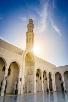 Sun is peeking from behind minaret at the  Mosque Muhammad al-Amin in Muscat, Oman