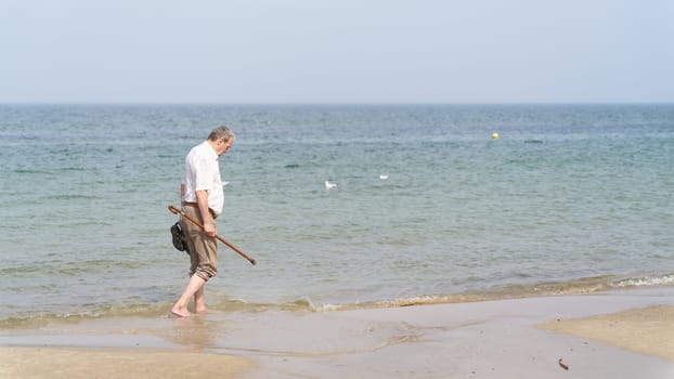 old man walking on the beach of the Baltic Sea near Kołobrzeg in Poland