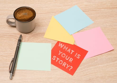 Story telling, cup coffee beside colorful paper, handwritten what is your story, concept business