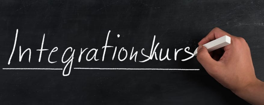 Words integration course are standing handwritten in the german language on a blackboard