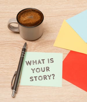 Story telling, cup coffee beside colorful paper, handwritten what is your story, concept business