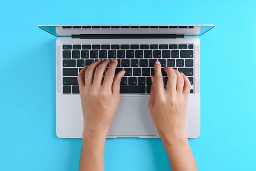 hand using laptop computer on blue background top view