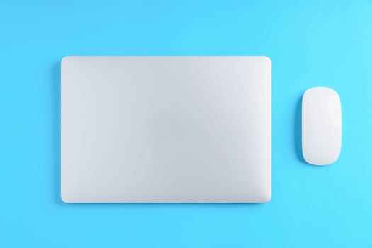 laptop computer and mouse on blue background above view