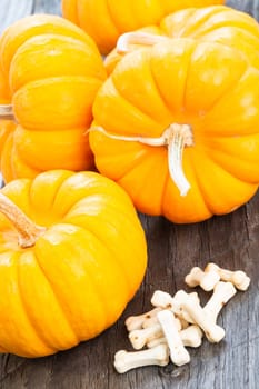 Halloween concept with miniature pumpkins and bones candy on wooden table