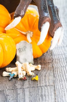 Halloween concept with miniature people, pumpkins, tombstone, bones candy and scary hand