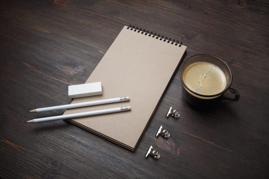 Blank kraft notepad, pencils, eraser and coffee cup on wooden background. Responsive design mockup.