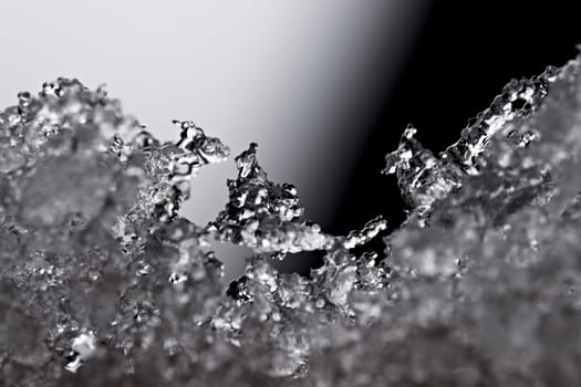 Thawing snow or frost, super macro close up image with an abstract background. Selective focus and soft black and white background. Microscopic detail