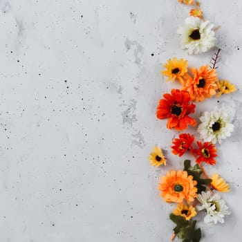 Light grey concrete flat lay background with colorful autumn flower heads, empty copy space area, gray textured surface. Autumn blossom composition. Flowers decoration top view. High quality photo