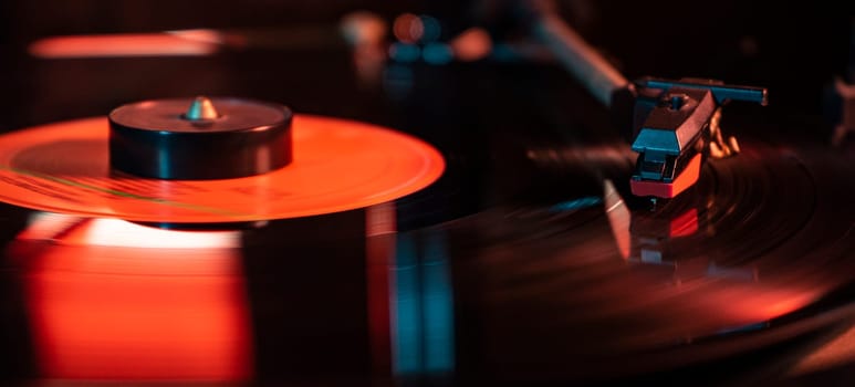 Needle detail on vinyl record on turntable, low light image with reflection