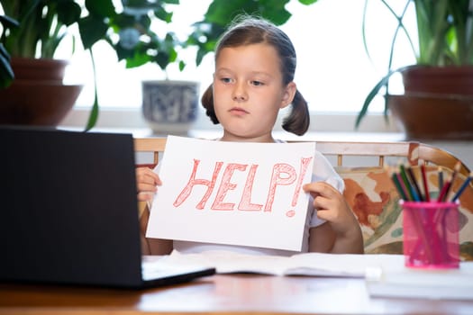 Distance learning concept. School girl holding help text during online education classes. COVID-19 pandemic forces children online learning.