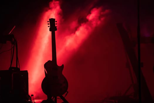 Acoustic guitar on the stage under beam of light with smoke with copy space. Music, summer festival concept.