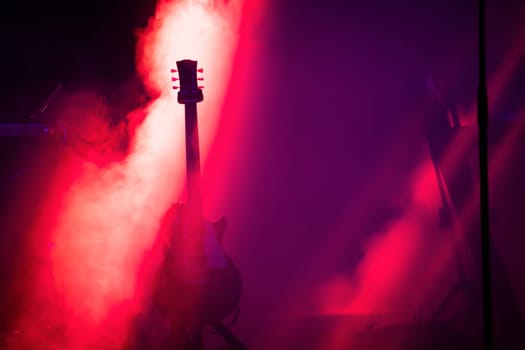 Acoustic guitar on the stage under beam of light with smoke with copy space. Music, summer festival concept.