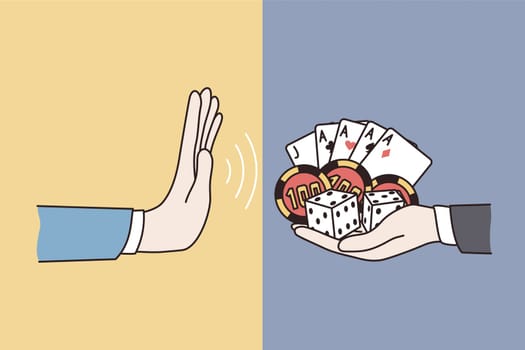 Refusal from gambling lifestyle concept. Human hand making no refusal denying sign from another hand holding cards and playing chips