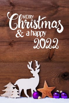Egnlish Calligraphy Merry Christmas And Happy 2022. Christmas Decoration With Tree, Deer And Purple Ball. Brown Wooden Background