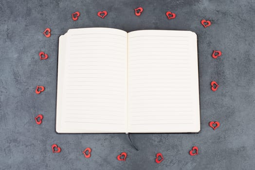 Empty notebook with wooden hearts and a pen
