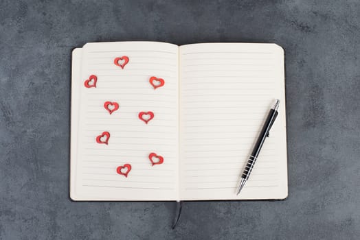 Empty notebook with wooden hearts and a pen