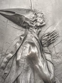 Bas-relief of an old pope in prayer on the bronze door of a church.