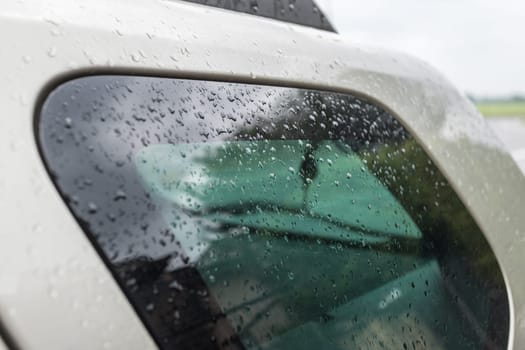 Raindrops on the car window and hood. Close up of water drops after rain at the car window. Season rain.