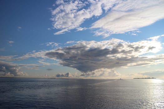 seascape cumulus clouds low over the sea island on the horizon evening