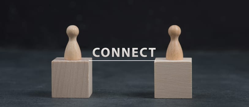 Two wooden persons connect to eachother, teamwork