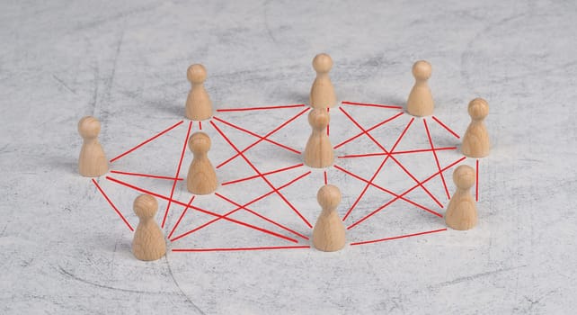 Group of wooden people connecting through red lines, communication between humans