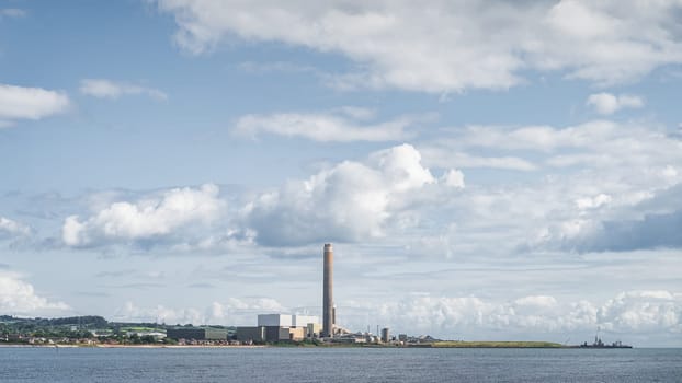 Large factory or plant with tall chimney and industrial harbour on the Northern Ireland coast, Carrickfergus town, County Antrim