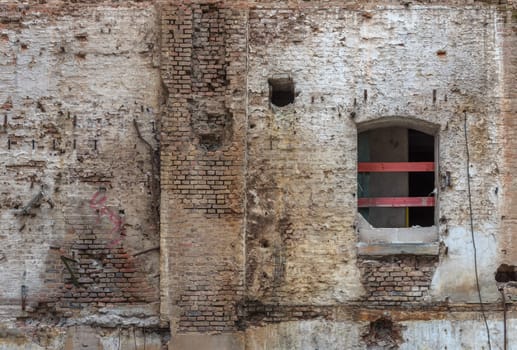 Broken red brick wall and damaged plaster on the background