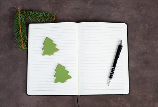 Empty notebook with christmas decoration, wooden trees, branch of fir