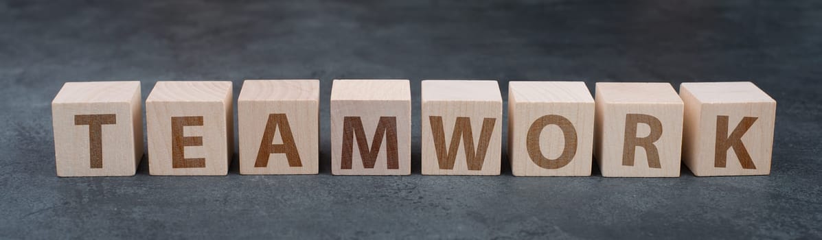 The word teamwork is standing on wooden cubes, dark background