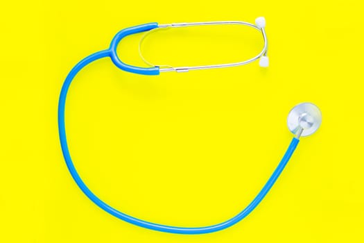 The blue phonendoscope lies in a circle on a yellow background. top view, flat lay, copy space, isolate.High quality photo