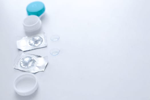 A container for lenses, two sealed lenses and lenses lying on a table on the side on a white background with a place for text. top view, flat lay, copy space, isolate. High quality photo