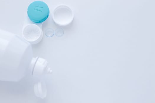 A container for lenses and two contact lenses lie on the side on a white background with space for text. top view, flat lay, copy space, isolate. High quality photo